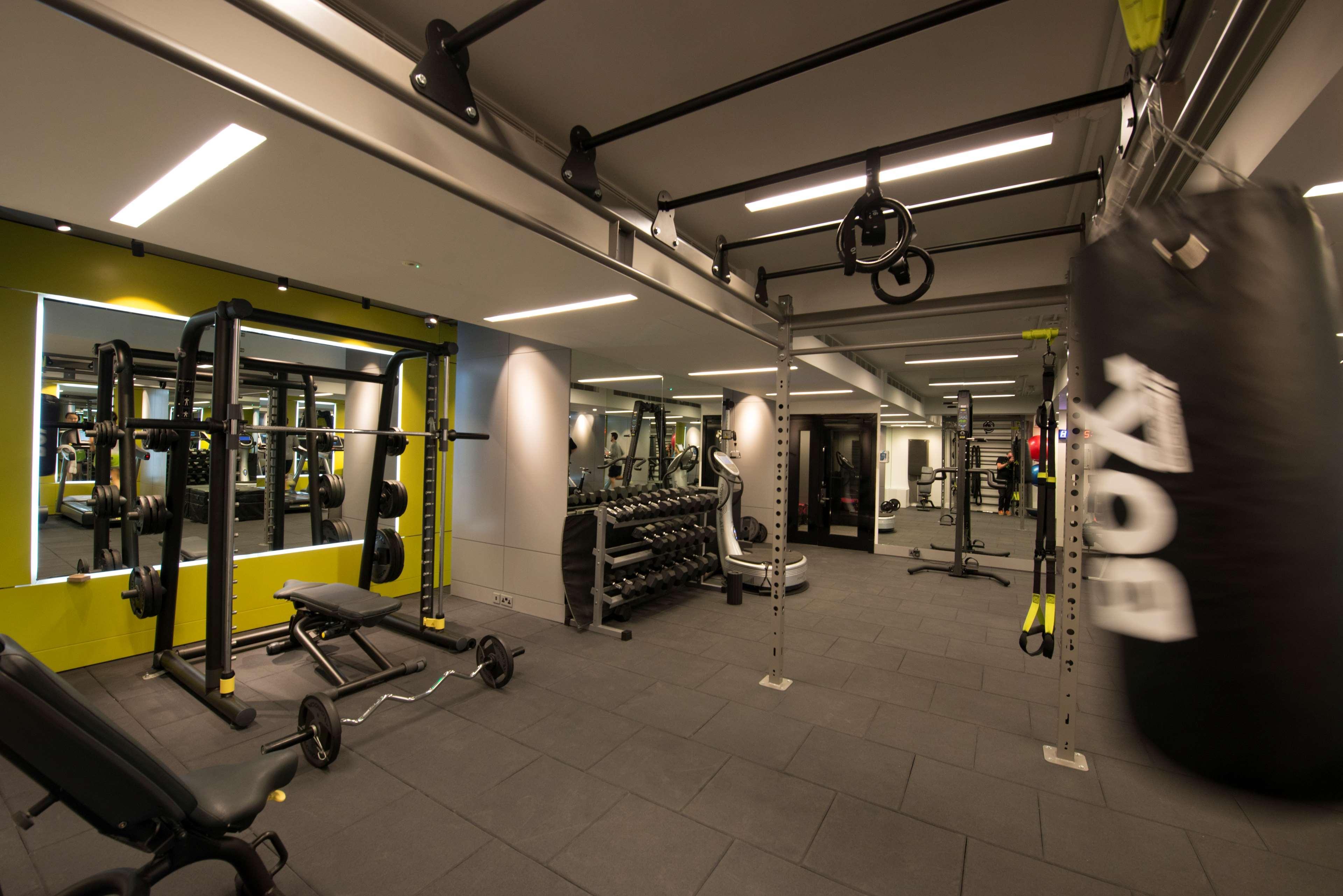 The May Fair, A Radisson Collection Hotel, Mayfair Londýn Exteriér fotografie The photo shows a modern gym interior. There are various fitness equipment pieces, including free weights, benches, and a multi-functional weight rack. The lighting is bright, with a mix of ceiling lights and mirrors on the walls that enhance the spa