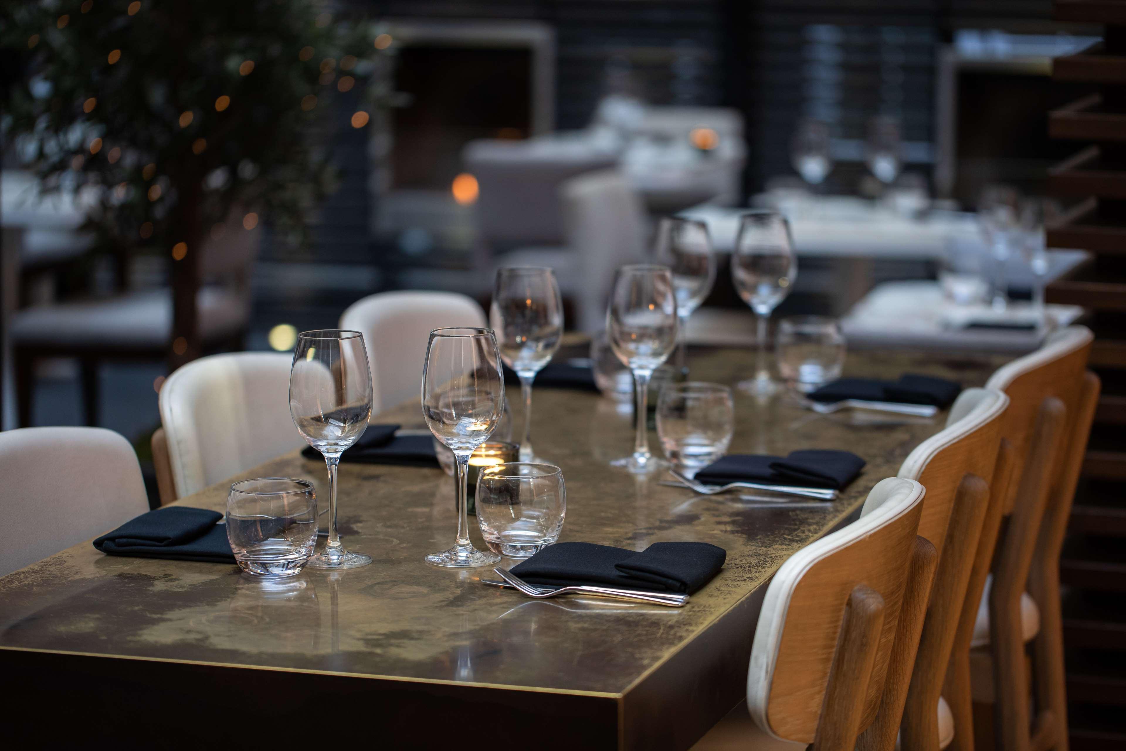 The May Fair, A Radisson Collection Hotel, Mayfair Londýn Exteriér fotografie The photo shows a dining table set for a meal. The table is made of a dark, polished material and has several place settings. Each setting features a wine glass, a smaller glass, and a neatly folded black napkin. The atmosphere appears elegant, with 