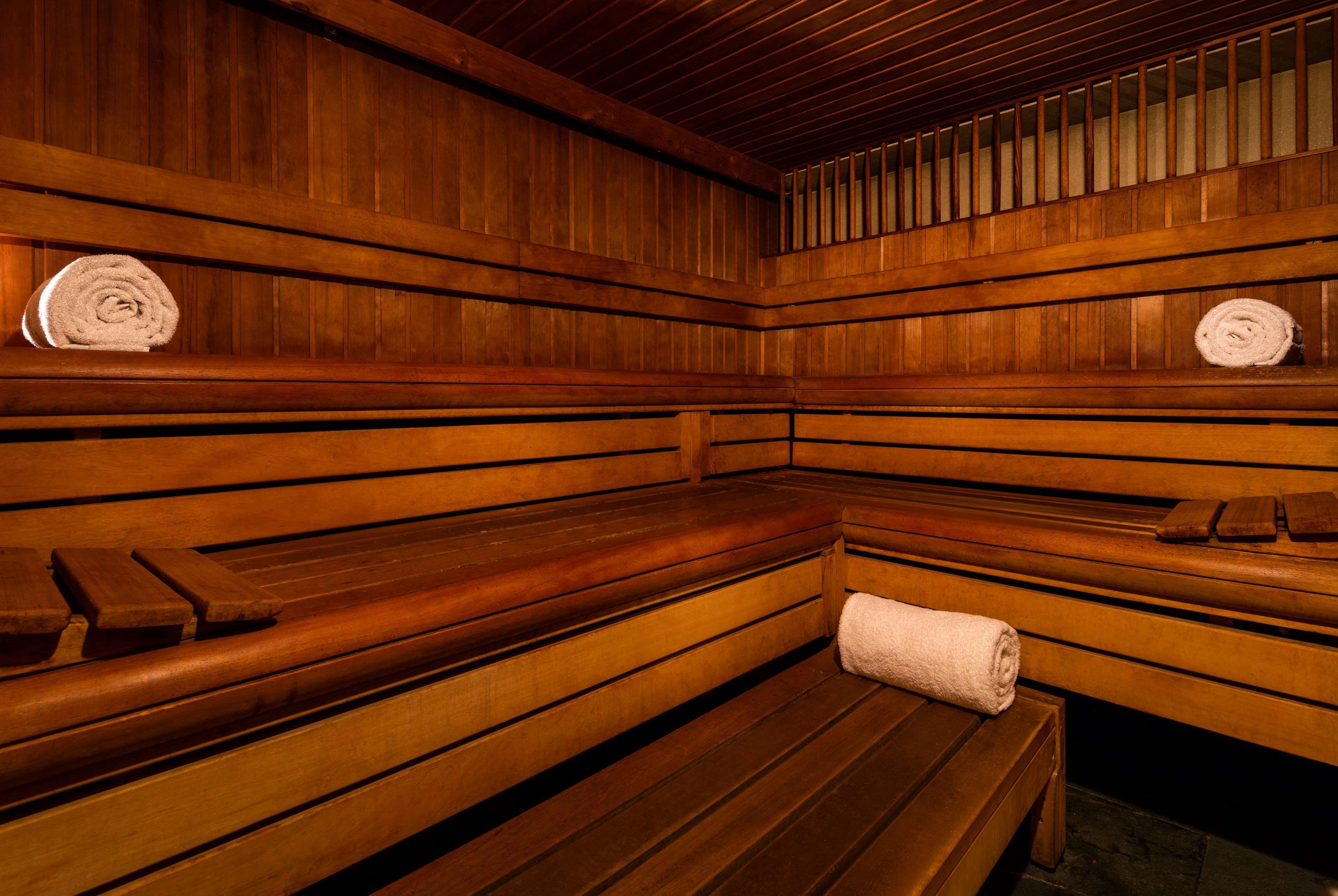 The May Fair, A Radisson Collection Hotel, Mayfair Londýn Exteriér fotografie The photo shows the interior of a sauna. It features wooden benches arranged along the walls, providing seating for visitors. There are neatly rolled white towels placed on the benches, giving a clean and inviting appearance. The walls and ceiling ar